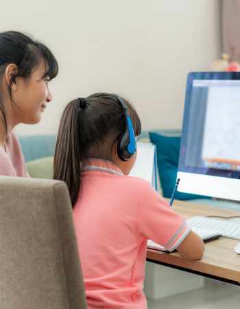 A woman and child do homework in front of a computer.