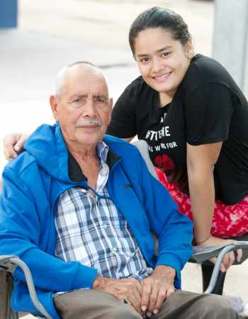 Older man sitting in chair with young woman standing behind