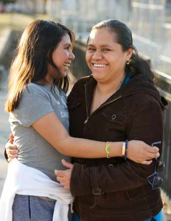 Mother daughter hugging on bridge