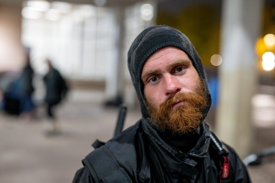 A man with a beard wearing a warm hat looking into the camera