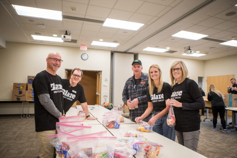 A group of smiling people making snack packs.