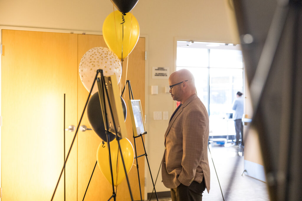 Armando Camacho, Wilder President and CEO looking at photos chosen by Unity school-based mental health graduates.