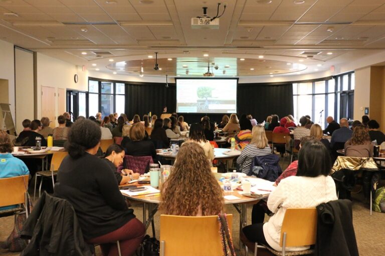 Photo of a conference room full of people listening to a speaker